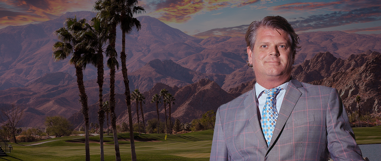 Christopher Donald Hewitt is standing with palms and a mountain in the background.
